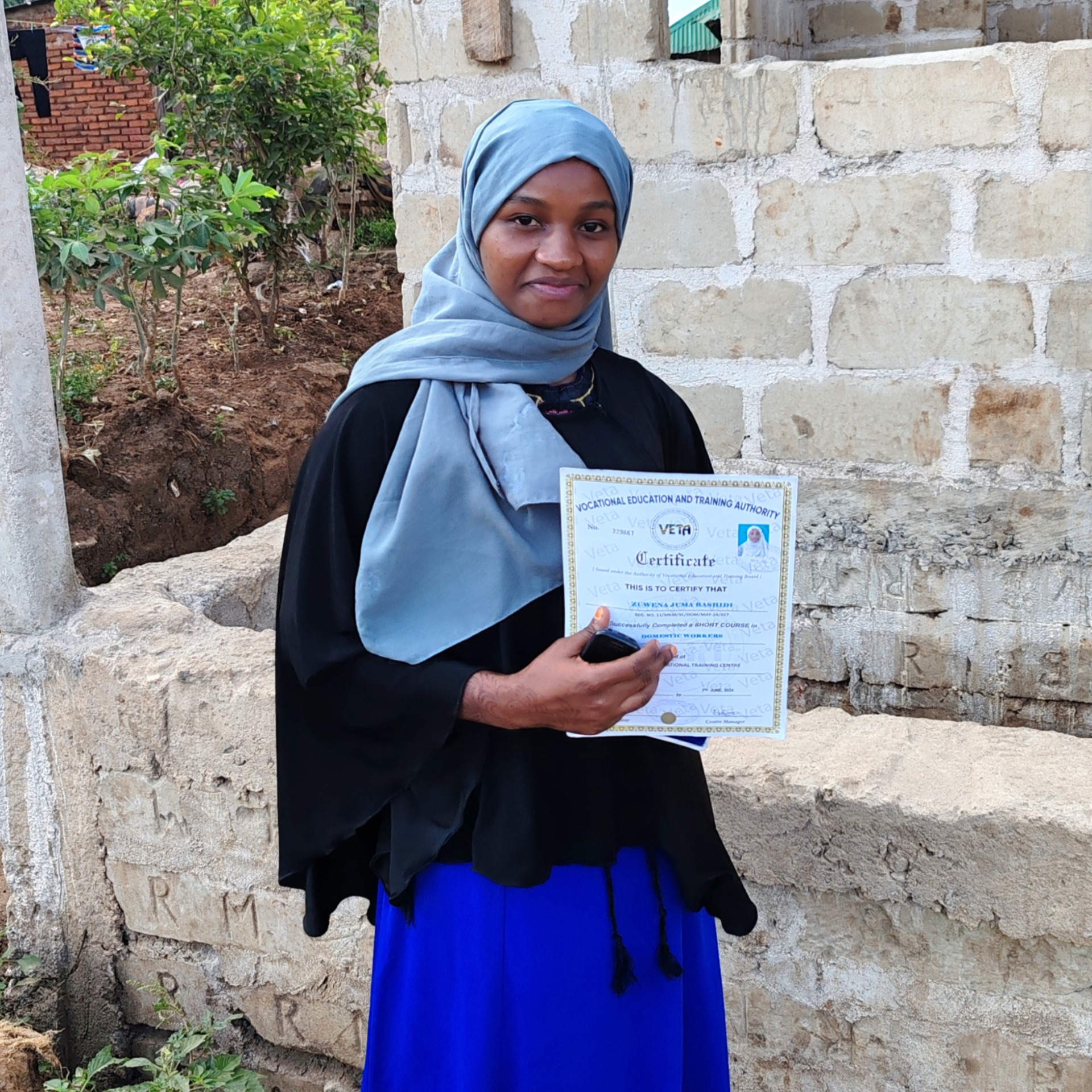 Zuwena, a Domestic worker from Tanzania with her professional certificate and union membership card. She completed the Professional Training course in Mikumi VETA centre in May 2024